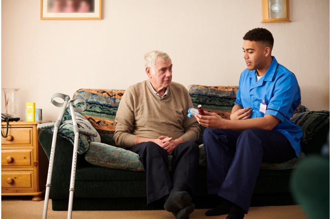 A care worker handing a client their daily medication at home